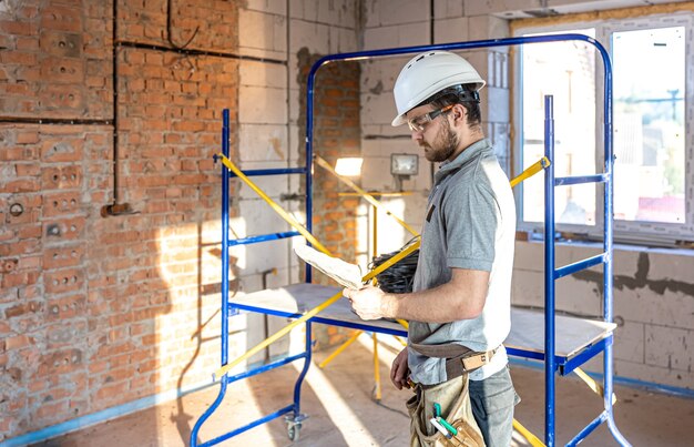 Un electricista examina un dibujo de construcción en un sitio de trabajo