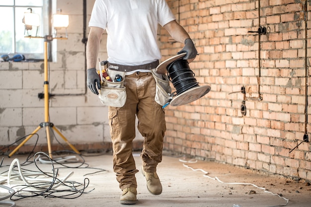 Electricista con herramientas, trabajando en un sitio de construcción. Concepto de reparación y manitas.