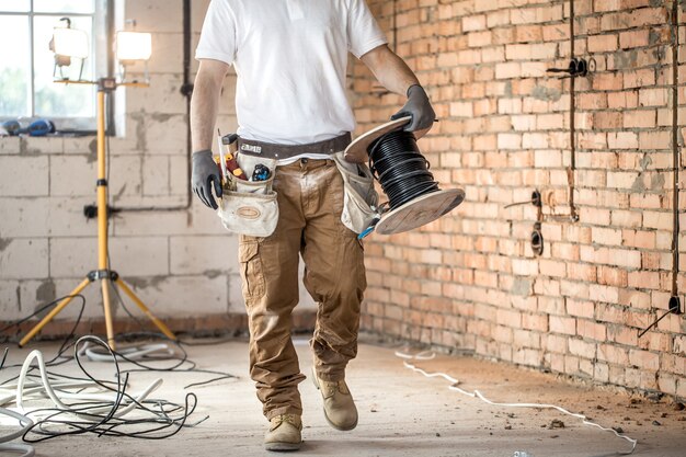 Electricista con herramientas, trabajando en un sitio de construcción. Concepto de reparación y manitas.