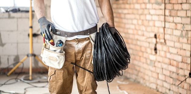 Electricista con herramientas, trabajando en un sitio de construcción. Concepto de reparación y manitas.