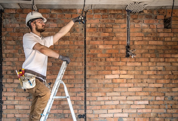 Electricista con herramientas, trabajando en un sitio en construcción