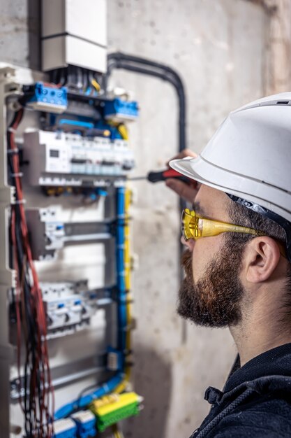 Un electricista masculino trabaja en una centralita con un cable de conexión eléctrica