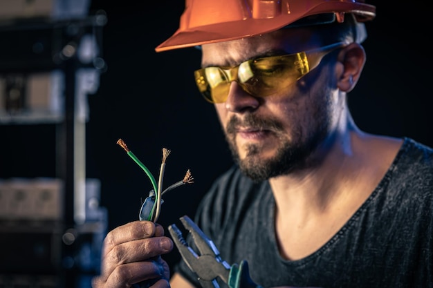 Foto gratuita un electricista masculino trabaja en un cuadro de distribución con un cable de conexión eléctrica