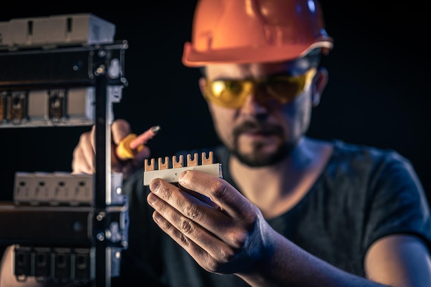 Foto gratuita un electricista masculino trabaja en un cuadro de distribución con un cable de conexión eléctrica