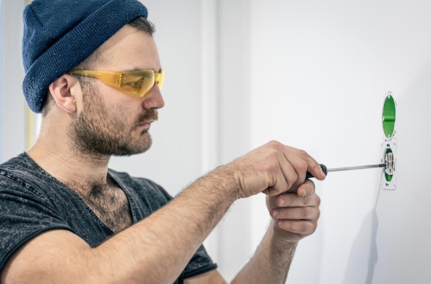 Foto gratuita un electricista está montando enchufes eléctricos en la pared blanca en el interior