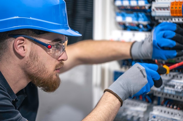 Un electricista trabaja en una central eléctrica con un cable de conexión eléctrica