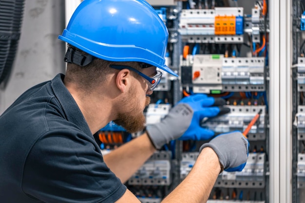 Un electricista trabaja en una central eléctrica con un cable de conexión eléctrica