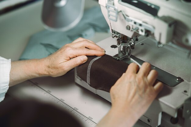 Elegante anciana sentada en estudio y coser tela