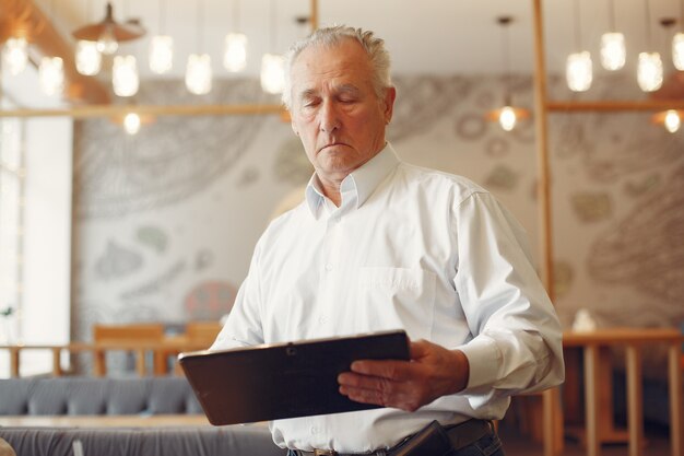 Elegante anciano en un café usando una computadora portátil