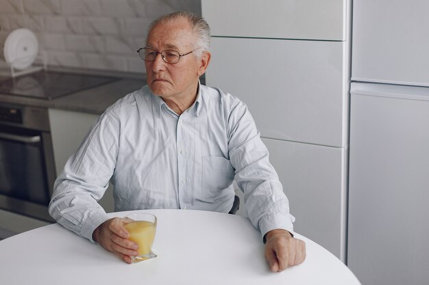 Elegante anciano en casa con jugo de naranja