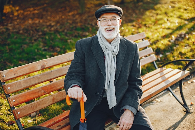 Elegante anciano en un parque soleado de otoño