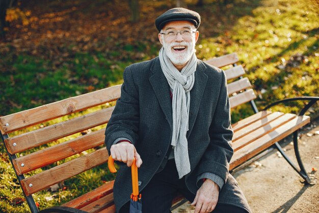 Elegante anciano en un parque soleado de otoño