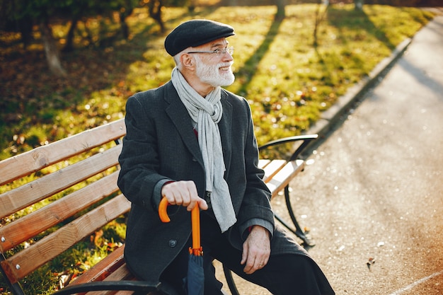 Elegante anciano en un parque soleado de otoño