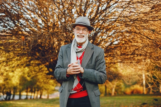 Elegante anciano en un parque soleado de otoño