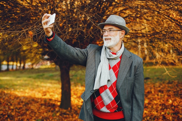 Elegante anciano en un parque soleado de otoño