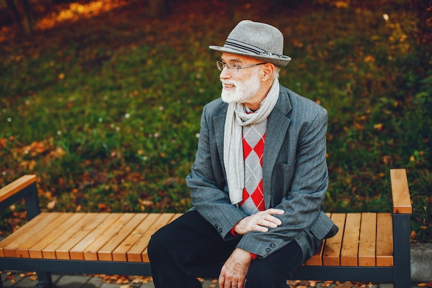 Elegante anciano en un parque soleado de otoño