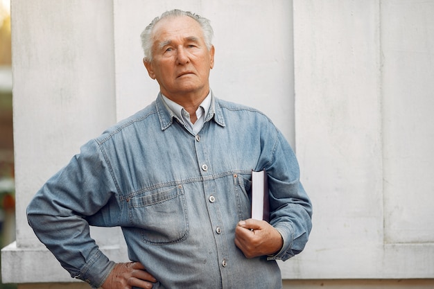 Foto gratuita elegante anciano de pie con un libro