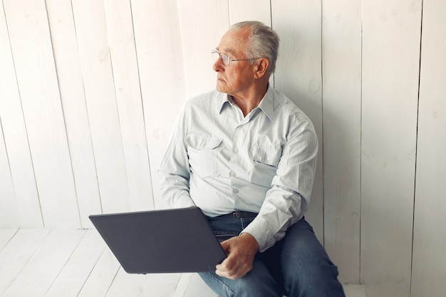 Foto gratuita elegante anciano sentado en casa y usando una computadora portátil