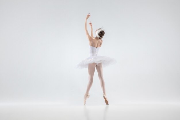 Elegante bailarina clásica bailando aislado sobre fondo blanco de estudio. Mujer con ropa tierna como personajes de cisne blanco. El concepto de gracia, artista, movimiento, acción y movimiento. Parece ingrávido.