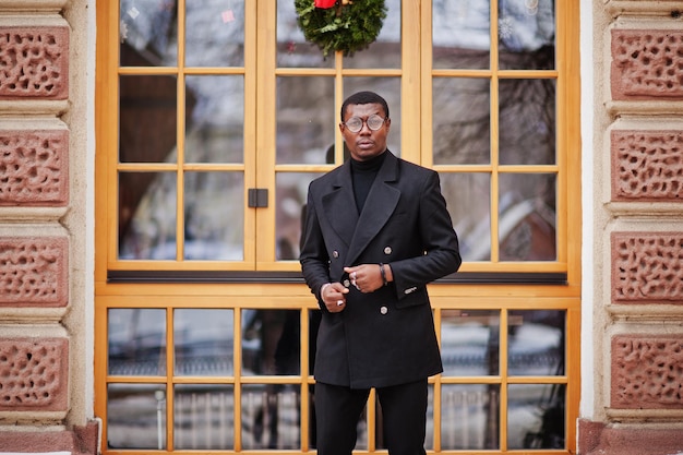 Foto gratuita elegante caballero afroamericano en elegante chaqueta negra rico hombre afro de moda contra la ventana