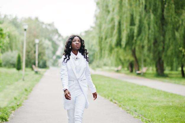 Elegante chica afroamericana negra caminando por la carretera en el parque