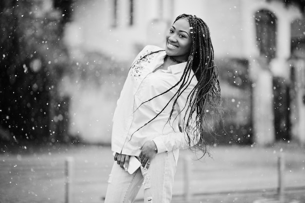 Elegante chica afroamericana con rastas sosteniendo el teléfono móvil a mano al aire libre clima nevado