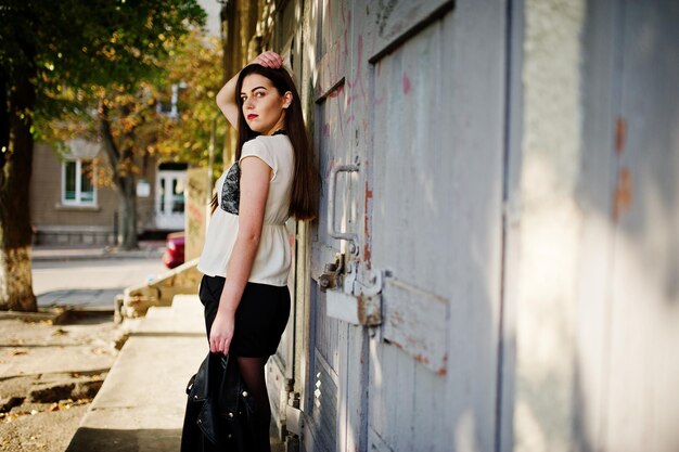 Elegante chica morena vestida con chaqueta de cuero y pantalones cortos posando en la calle