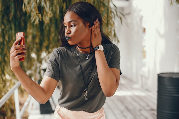 Elegante chica negra en una ciudad de verano.