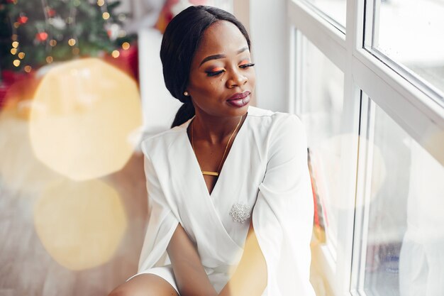 elegante chica negra en una habitación en Navidad