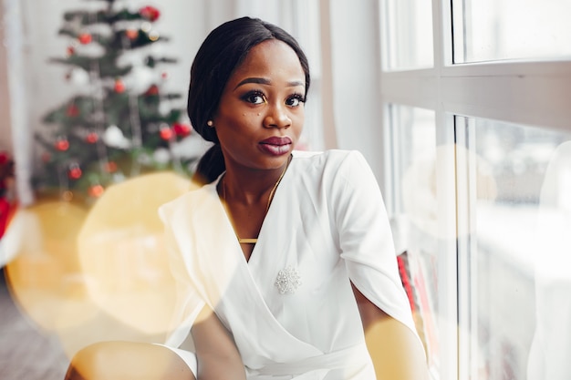 elegante chica negra en una habitación en Navidad