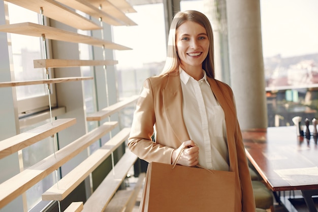 Elegante chica de pie en una cafetería con bolsas de compras