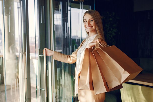 Elegante chica de pie en una cafetería con bolsas de compras