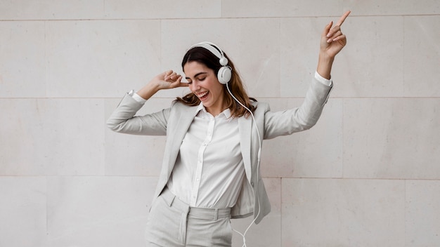 Foto gratuita elegante empresaria escuchando música en auriculares