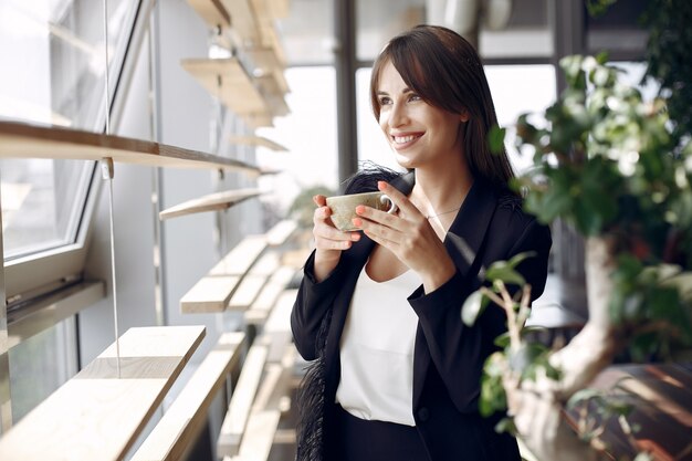 Elegante empresaria trabajando en una oficina y tomando un café