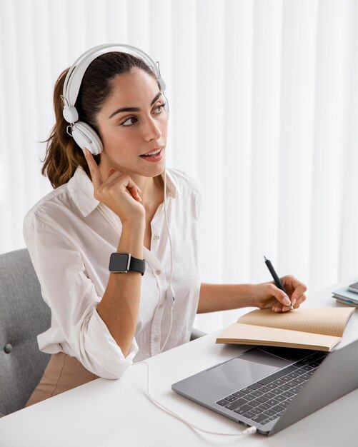 Elegante empresaria trabajando con portátil y auriculares