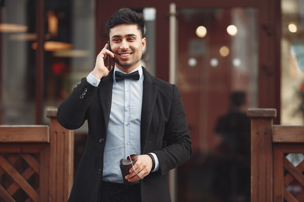 Elegante empresario en un traje negro de pie afuera