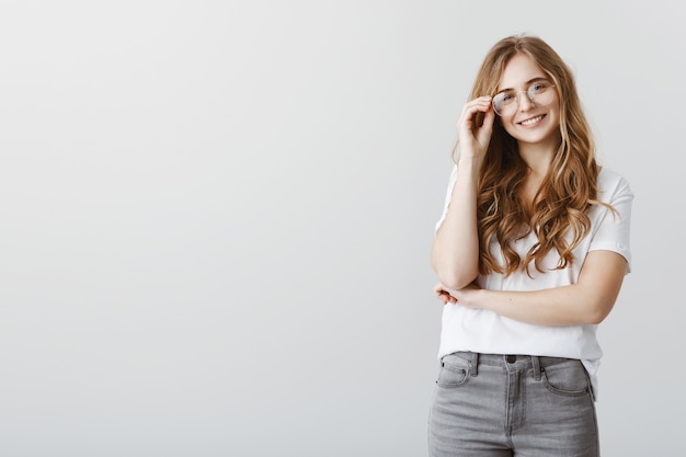 Elegante estudiante rubia sonriente en gafas mirando feliz