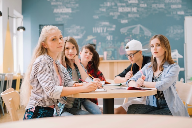 Elegante estudiantes sentados en el escritorio