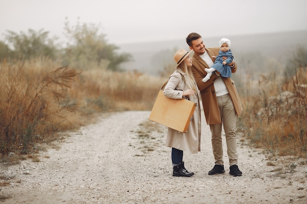 Elegante familia caminando en un campo de otoño