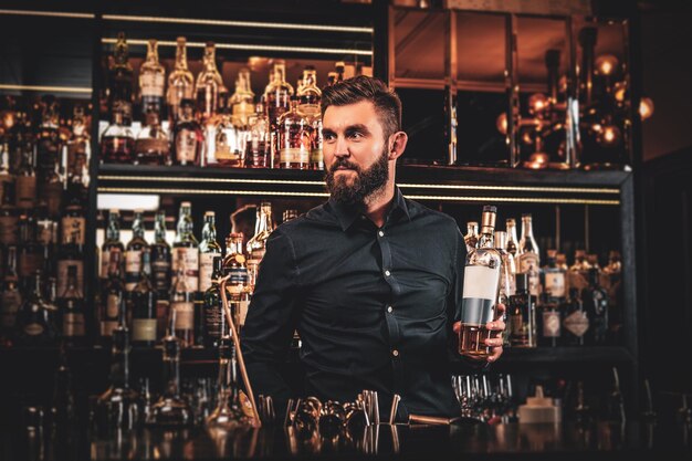El elegante y feliz propietario del bar prepara una bebida especial para sus clientes en su propio bar.