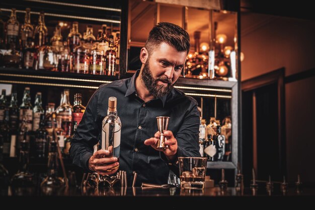 El elegante y feliz propietario del bar prepara una bebida especial para sus clientes en su propio bar.