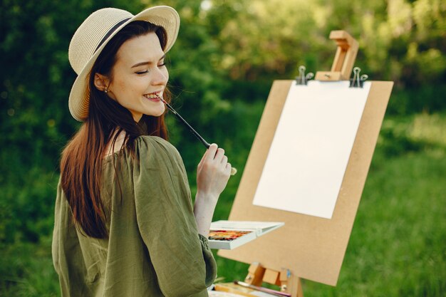 Elegante y hermosa niña pintando en un campo