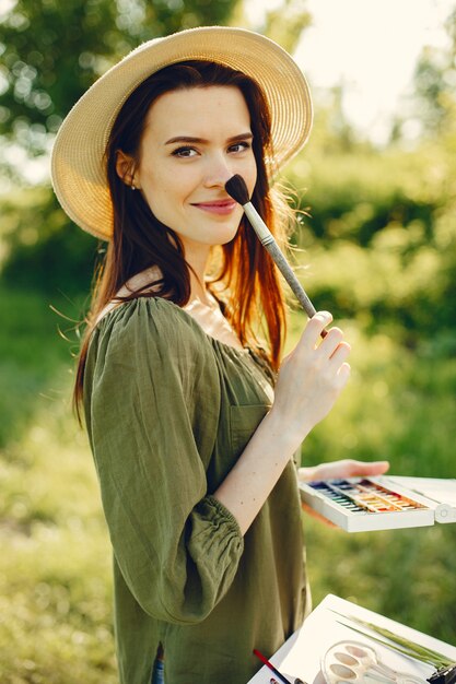 Elegante y hermosa niña pintando en un campo