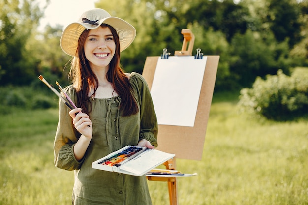 Elegante y hermosa niña pintando en un campo