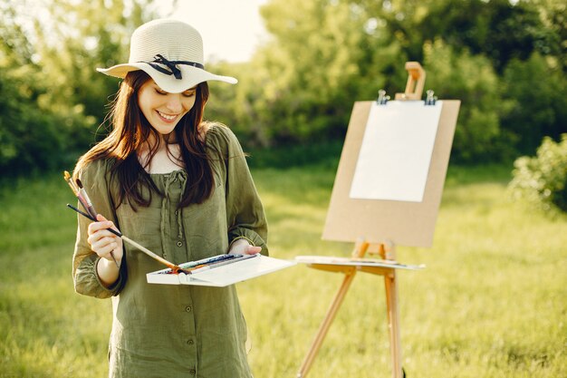 Elegante y hermosa niña pintando en un campo