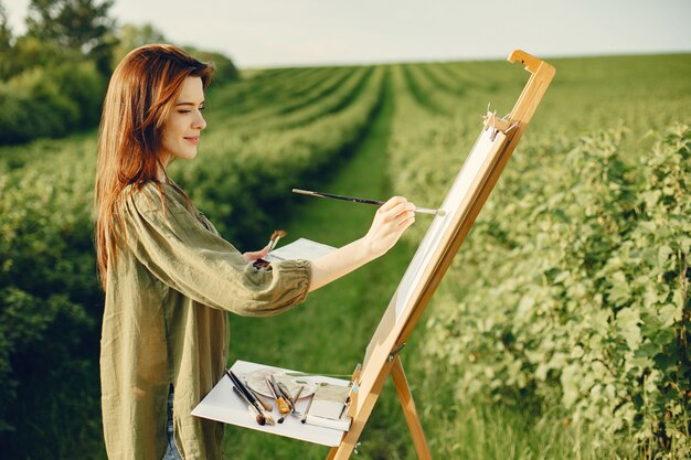 Elegante y hermosa niña pintando en un campo