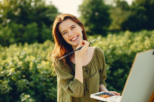 Elegante y hermosa niña pintando en un campo