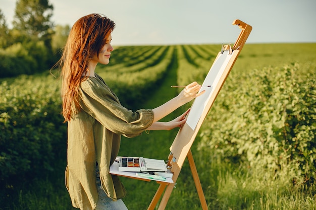 Elegante y hermosa niña pintando en un campo