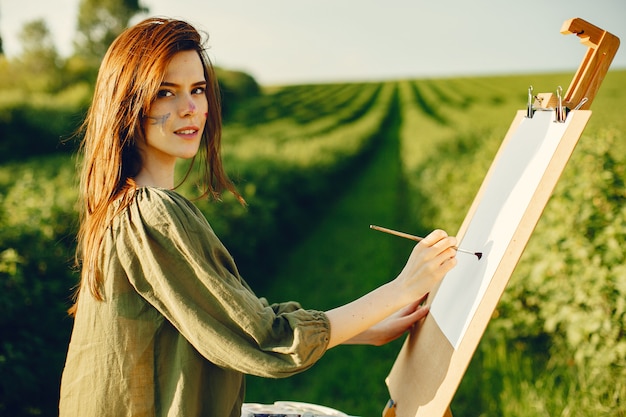 Elegante y hermosa niña pintando en un campo