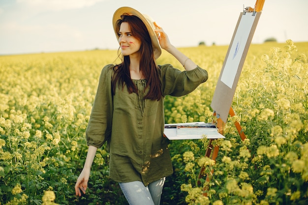 Elegante y hermosa niña pintando en un campo